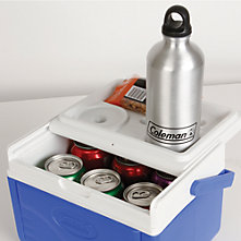 A small Coleman beverage cooler with the lid slid open to reveal several cans on the inside and a Coleman-branded stainless steel water bottle resting in the cup holder on the lid. A small bag of peanuts is also sitting on the lid behind the water bottle.