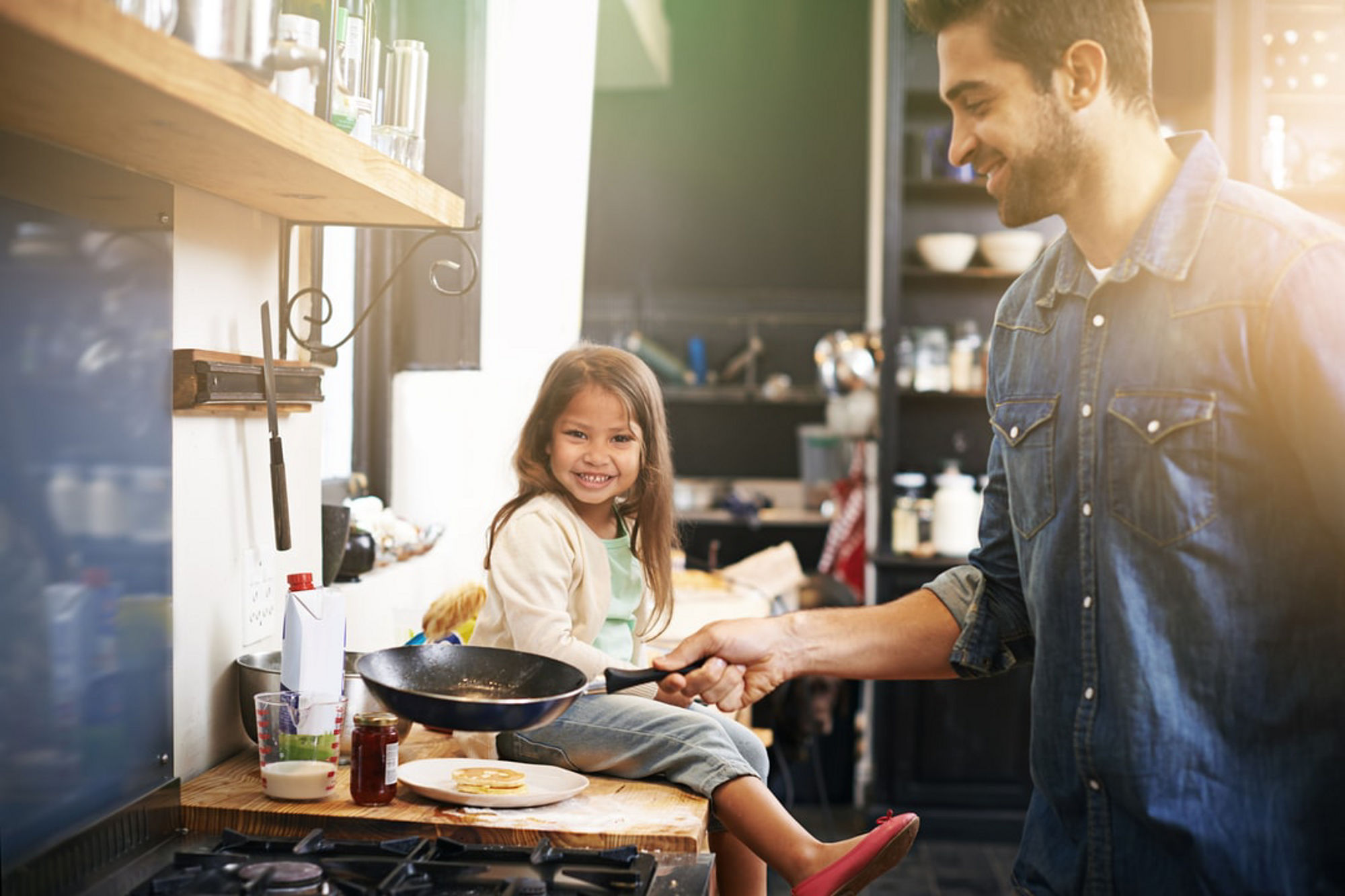 An adult and a child prepare food together in a modern home kitchen, creating a warm, everyday scene of cooking and shared time.