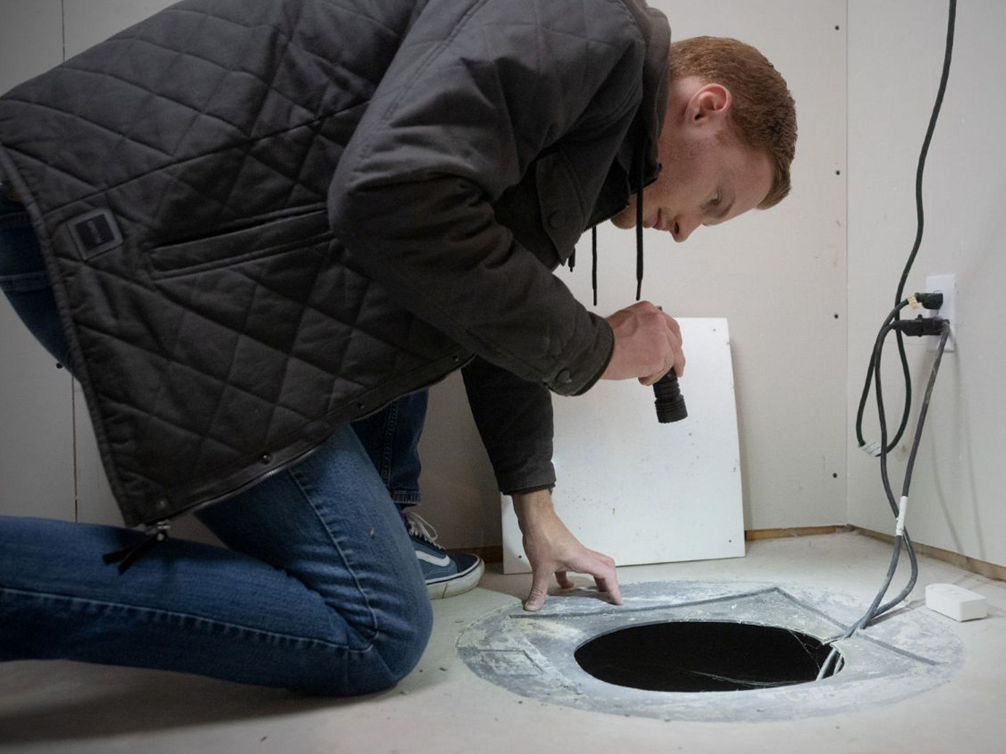 A homeowner inspects a sump pump in a basement to ensure it is working properly.