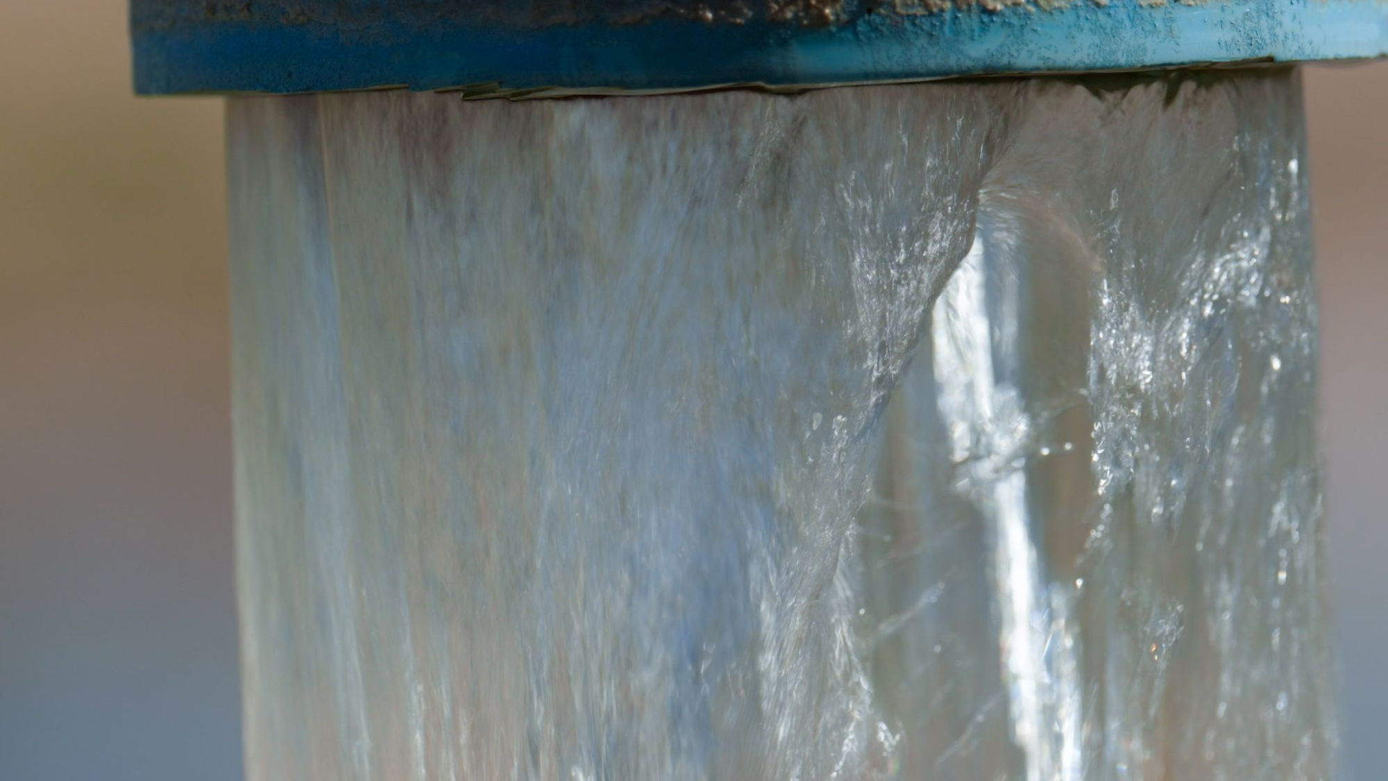 Close up of clean water flowing from a pipe into another container.