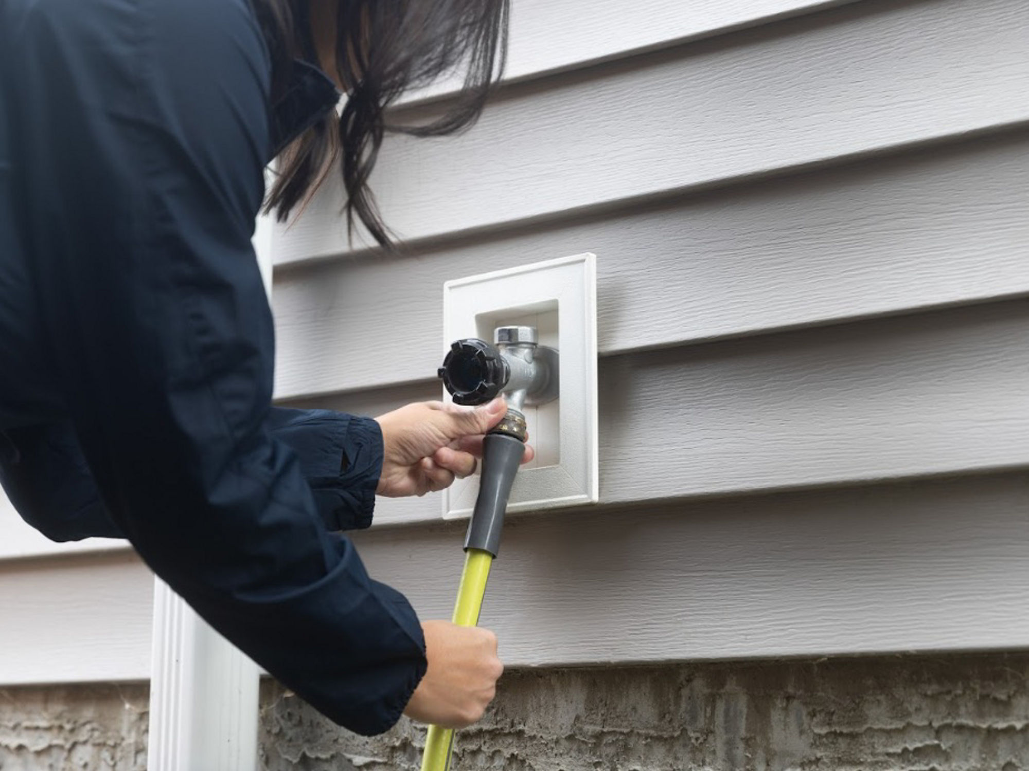 Someone disconnecting their outside water hose for winter.