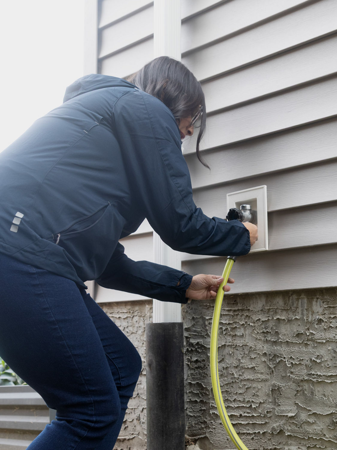 Someone turning off and disconnecting the outdoor water hose faucet.