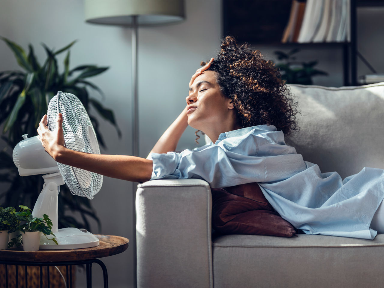 Woman sitting in front of a fan blowing air
