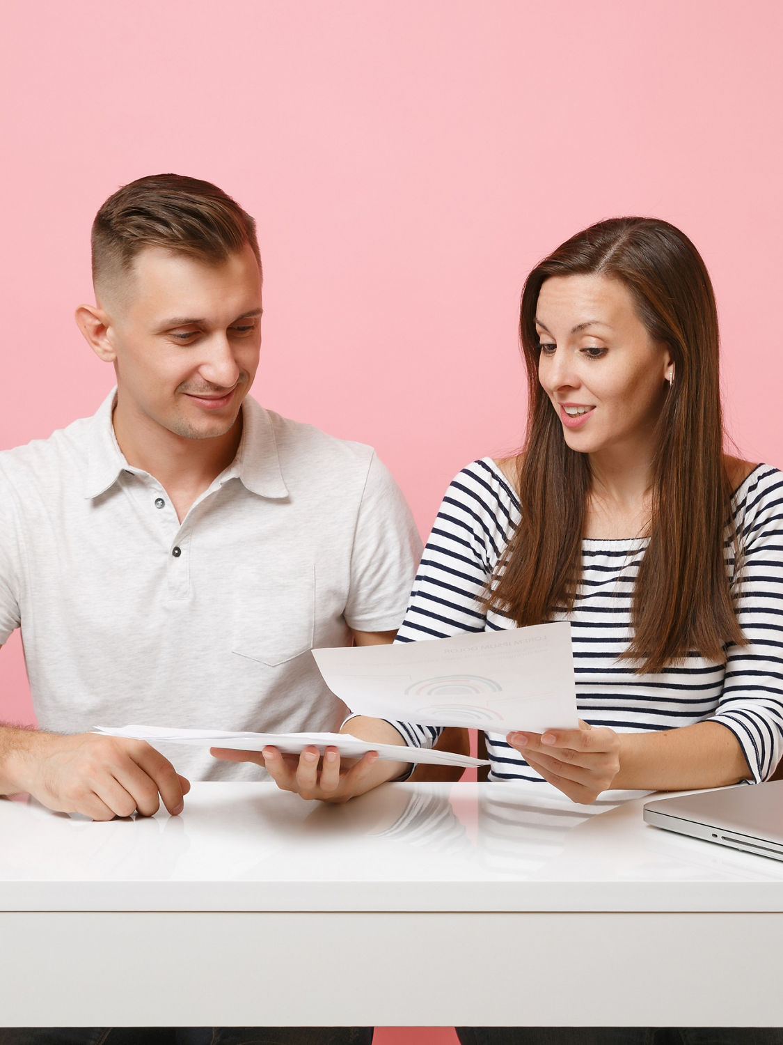 Two young smiling business woman man colleagues sit work at white desk with paper documents isolated on pastel pink background. Achievement career concept. Copy space advertising, youth co working