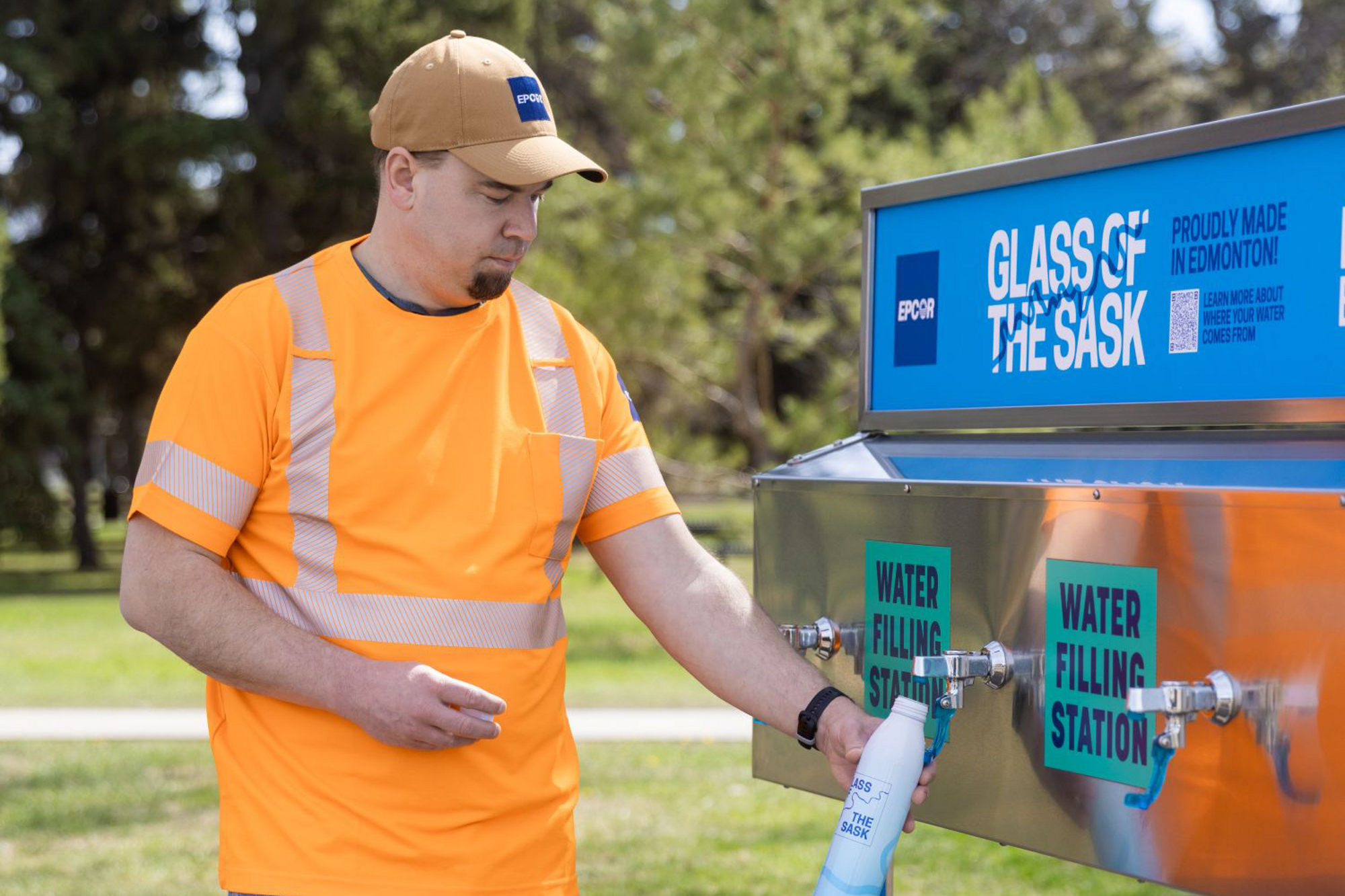 EPCOR employee standing next to a Glass of the Sask water station filling reusable bottle.