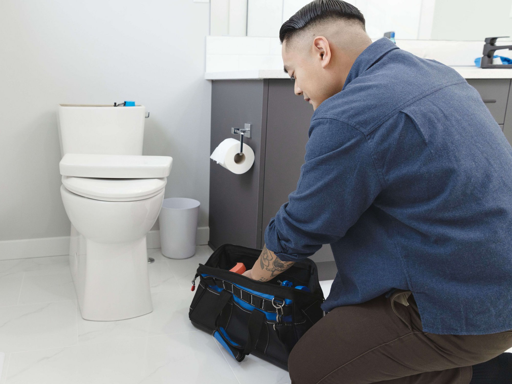 A man getting a tool out of his toolkit to fix leaky toilet.