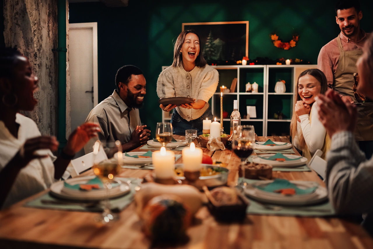 Happy multi-ethnic friends and family are laughing and enjoying a festive meal together at home