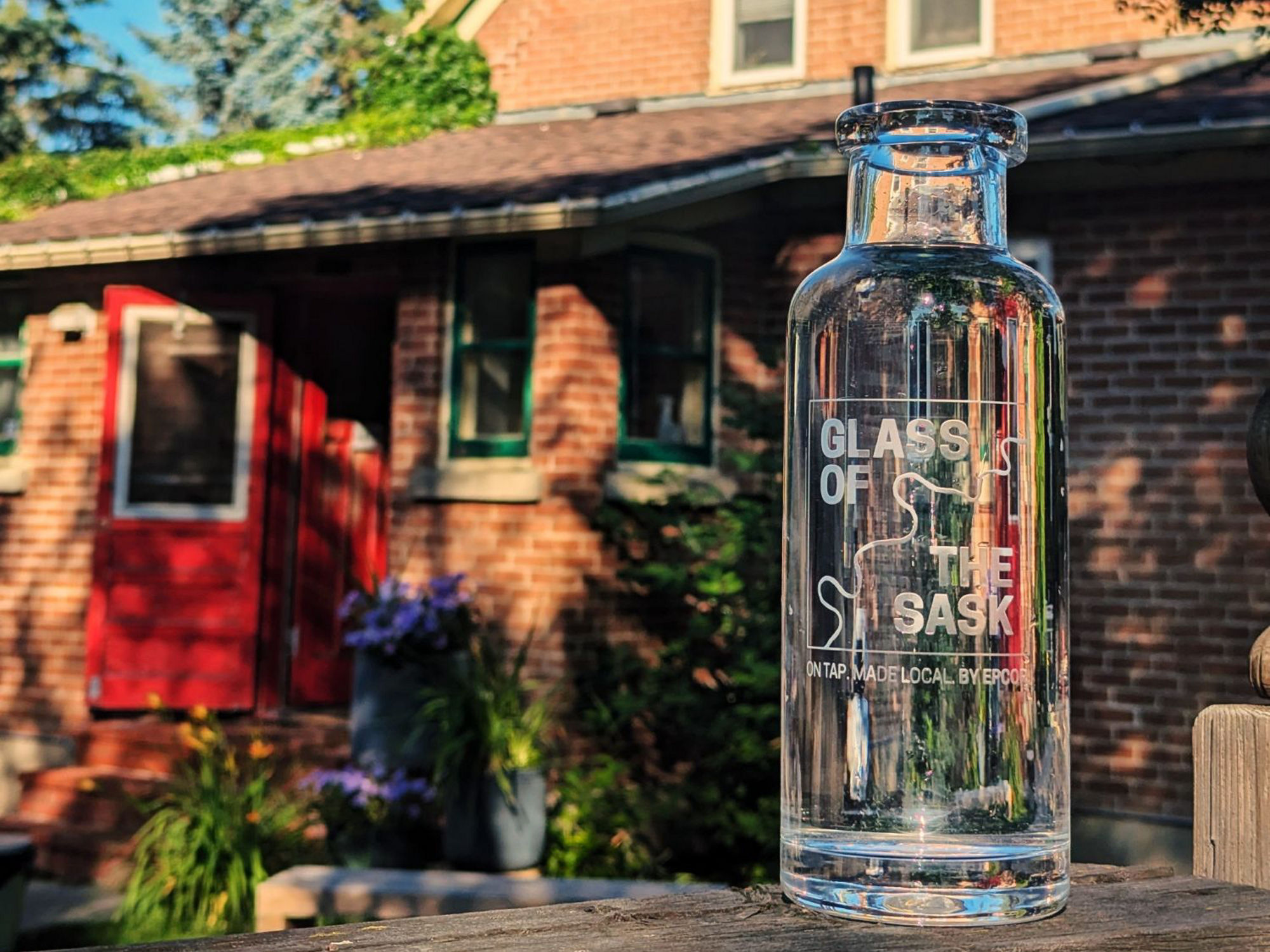 A Glass of the Sask carafe full of water sitting on a fence outside the restaurant, Little Brick.