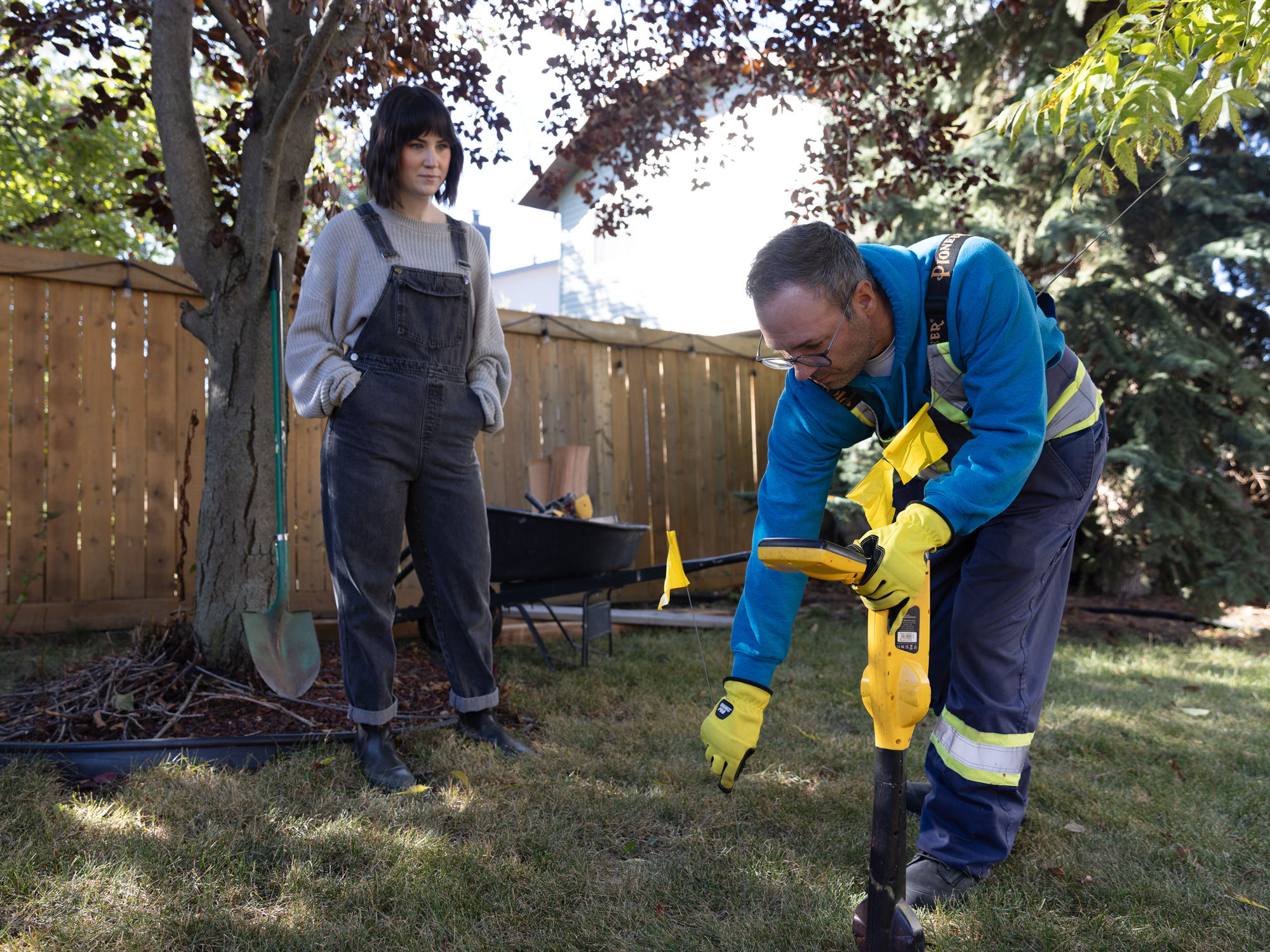 Homeowner observing while a technician locates underground utilities before digging in yard..