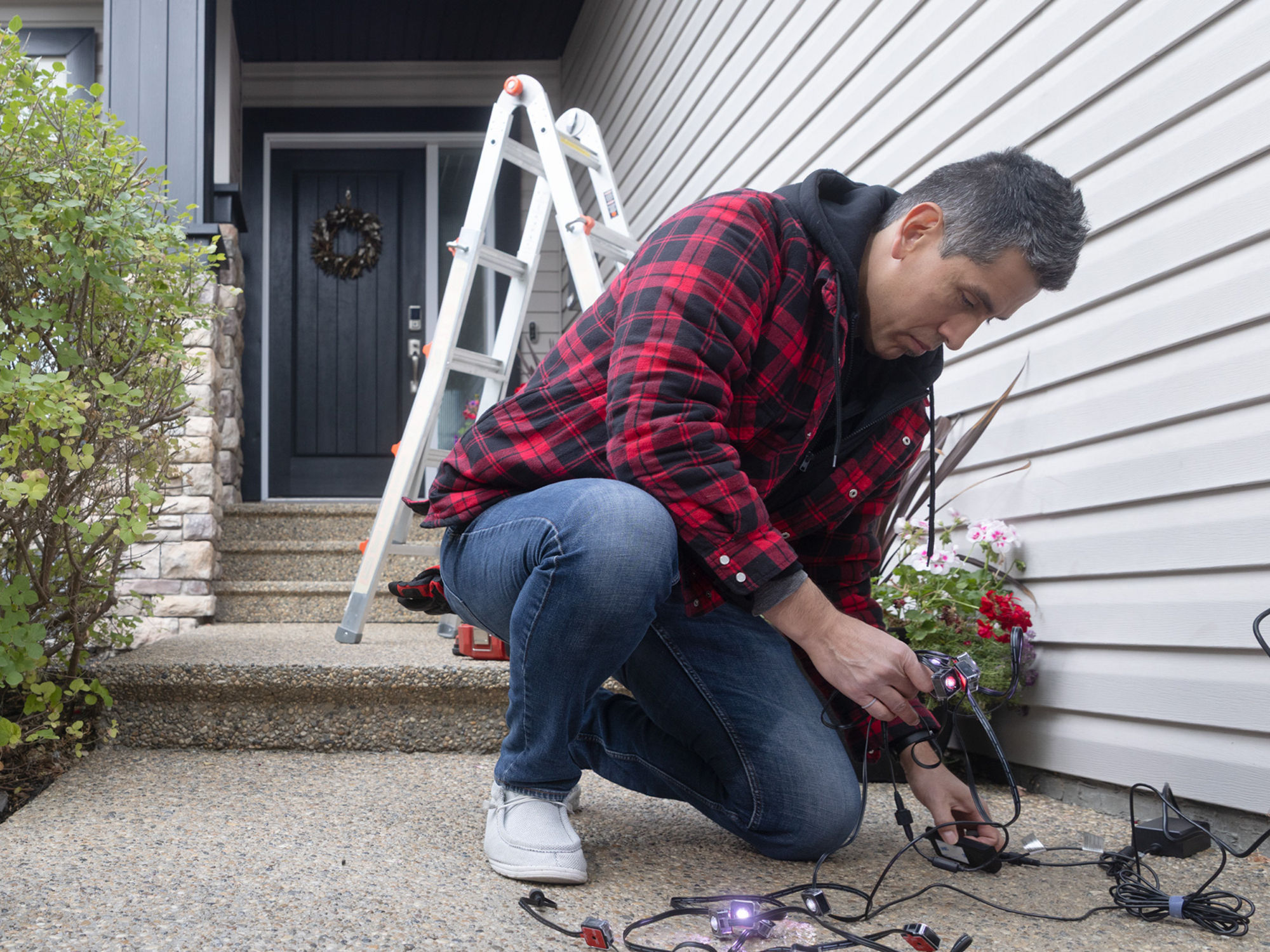 A person inspecting holiday string lights outside before putting on home. 