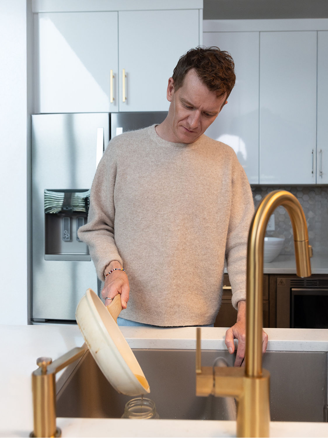 A man pouring grease from a frying pan into a jar.