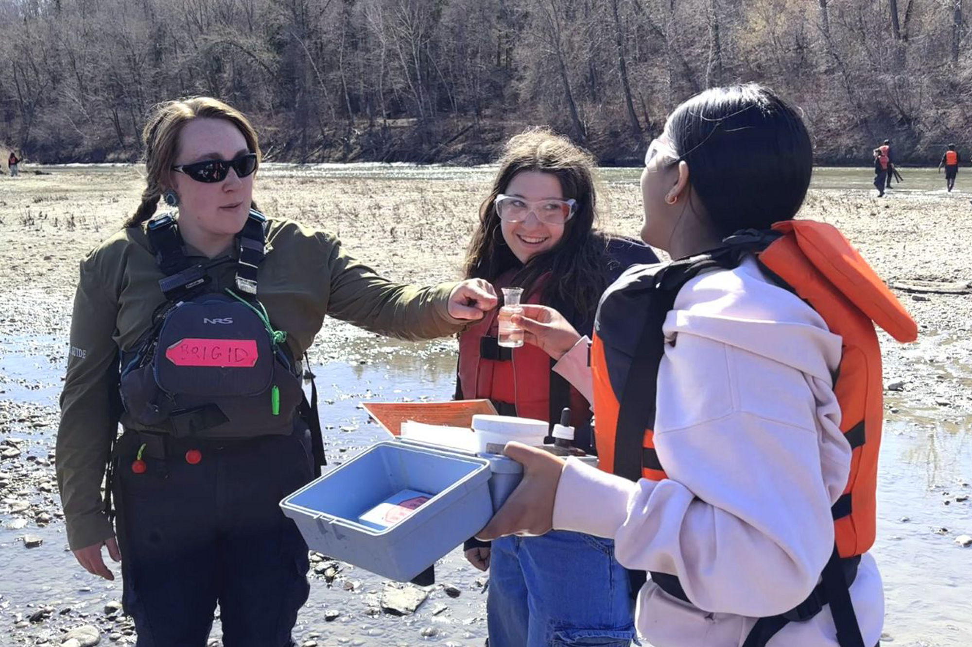 RiverWatch guide testing water quality with two female students during an all-girls float. 