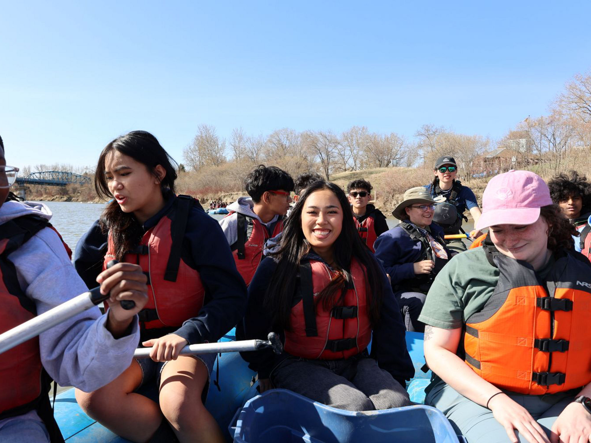 Group of students smiling on blue raft during RiverWatch float.
