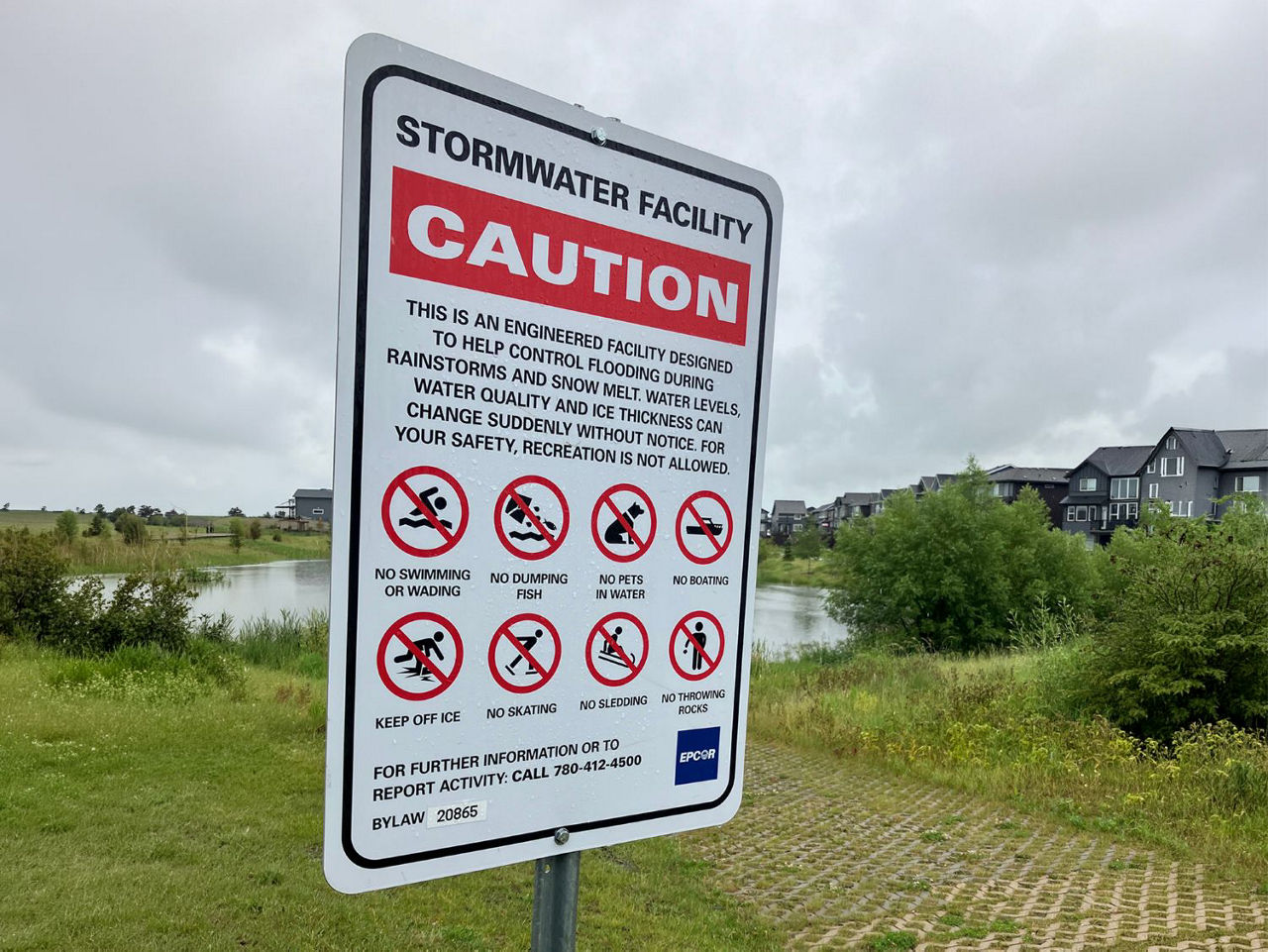 Caution sign location near stormwater pond in residential neighbourhood.