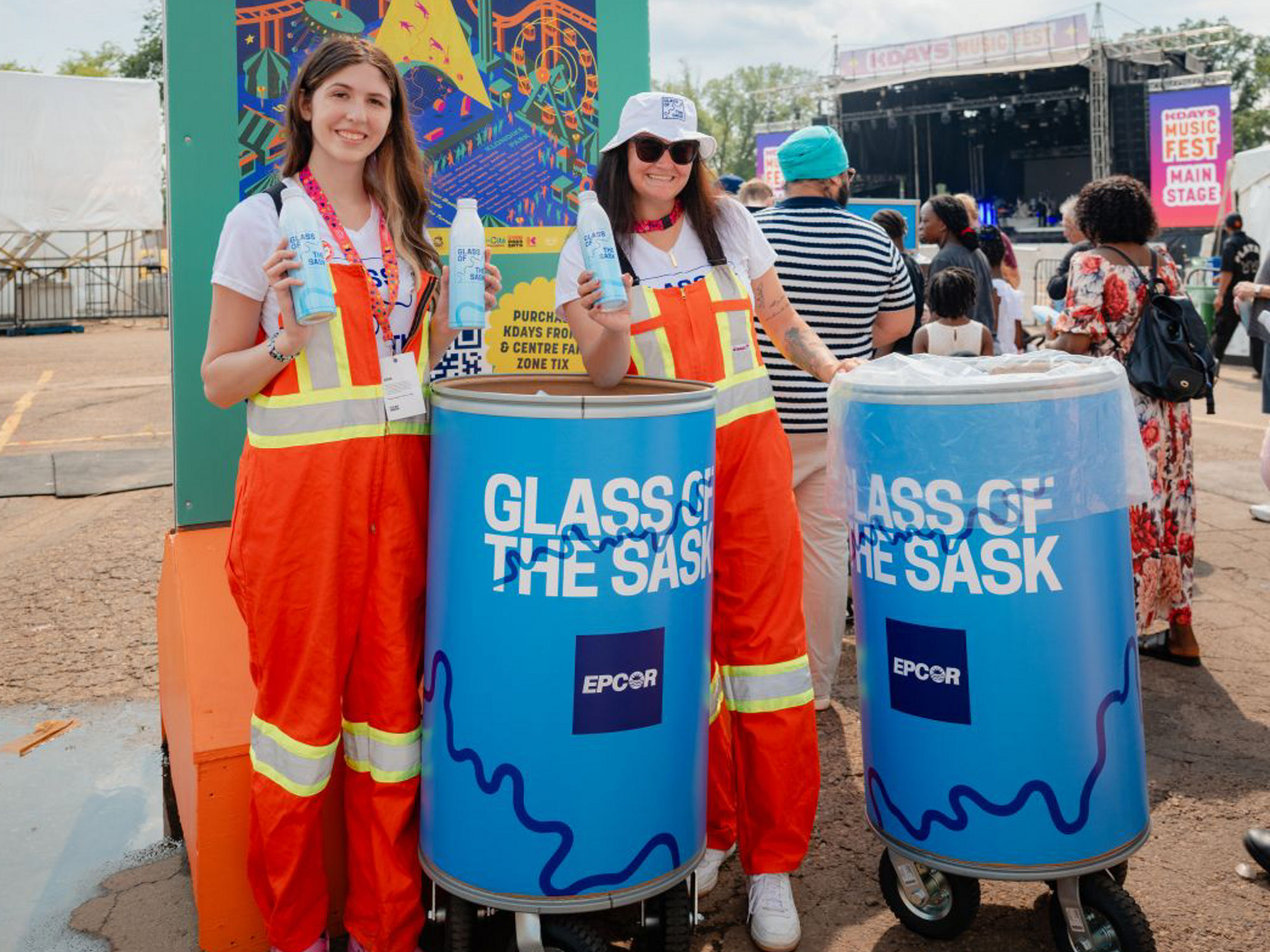 Two women in orange overalls handing out free Glass of the Sask aluminum bottles at a KDays event.