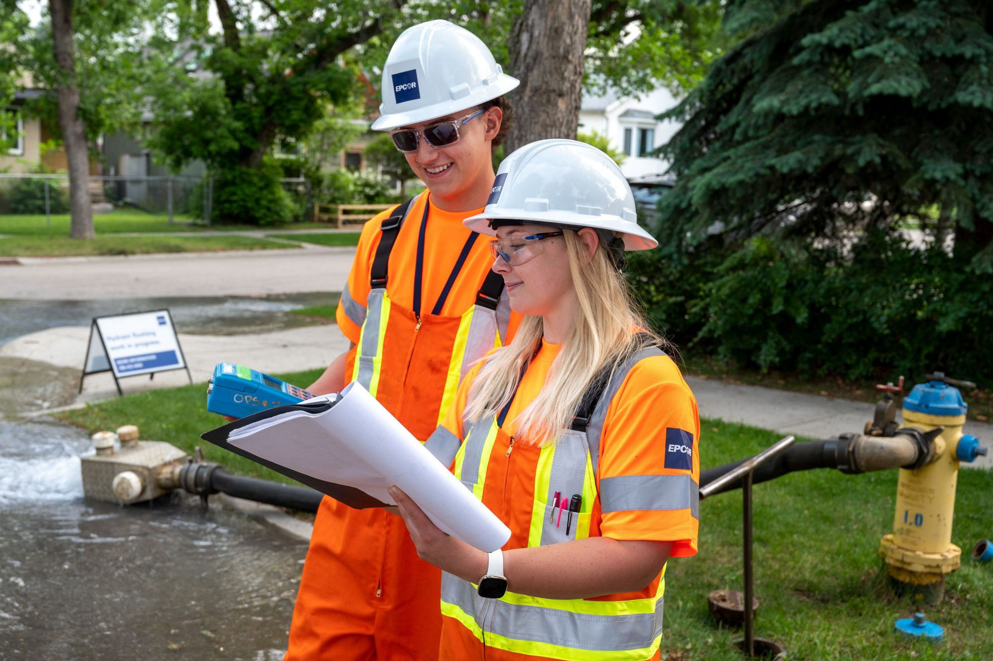 Utility field workers review documentation during on‑site maintenance of municipal water infrastructure in a residential neighbourhood, demonstrating safe and reliable water system operations.