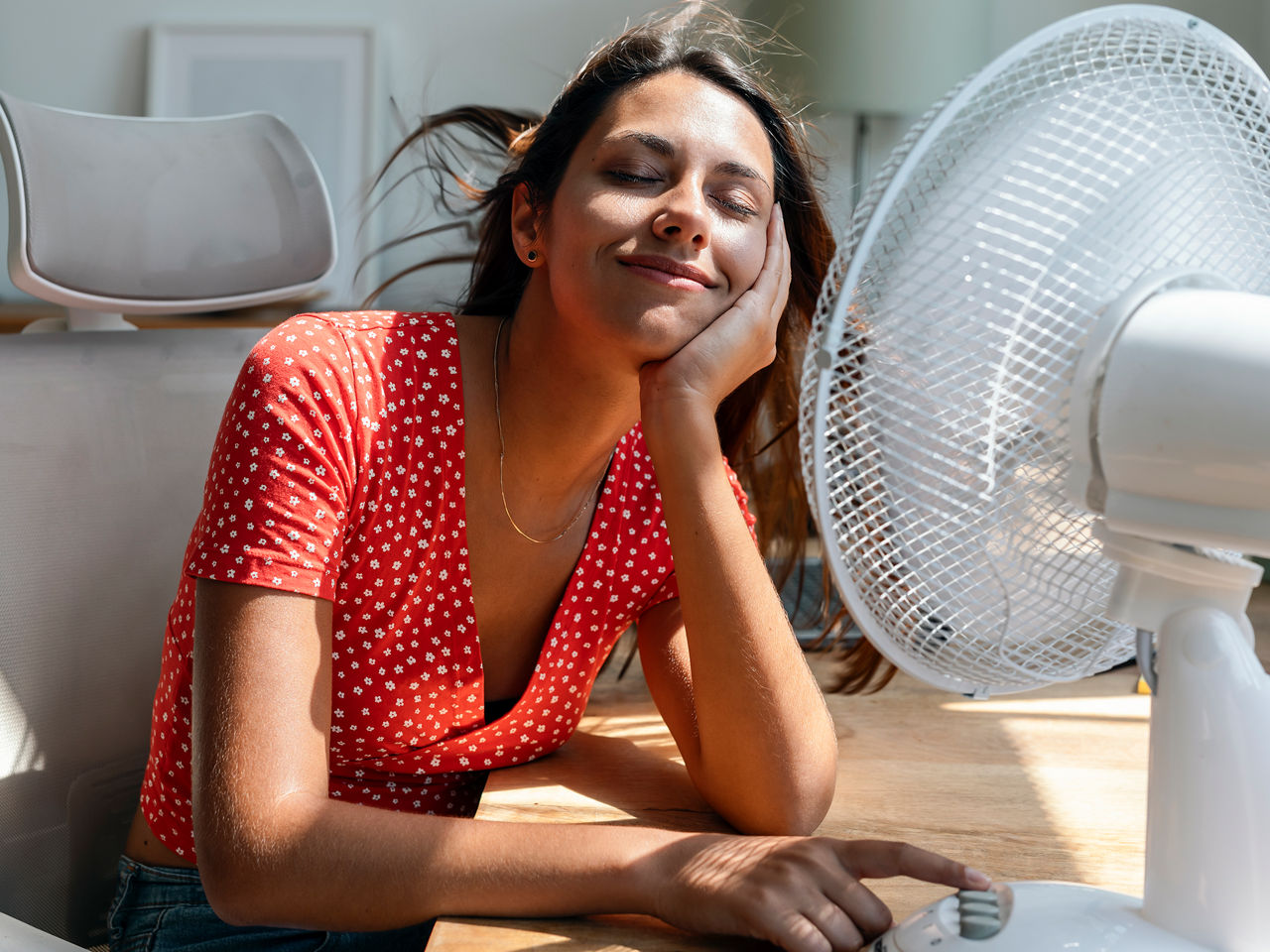 Woman sitting in front of a fan blowing air