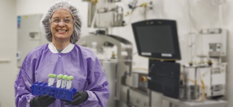 Lab scientist holding sample vials in cleanroom facility