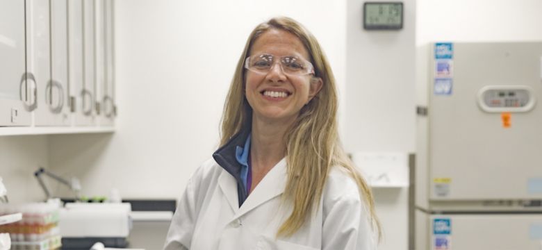 Smiling female scientist posing at laboratory workbench