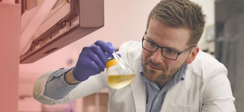 Male scientist examining liquid sample in Erlenmeyer flask in laboratory