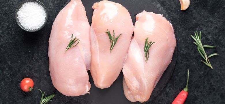 Three raw chicken breasts on stone background