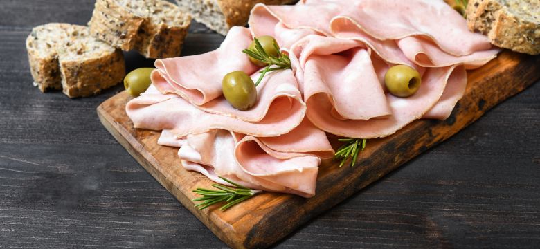 Traditional Italian antipasti mortadella on a wooden plate, served with olives