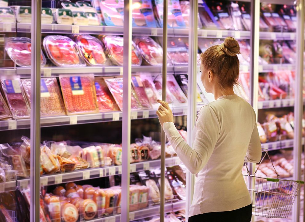 Supermarket girl in front of cold cuts