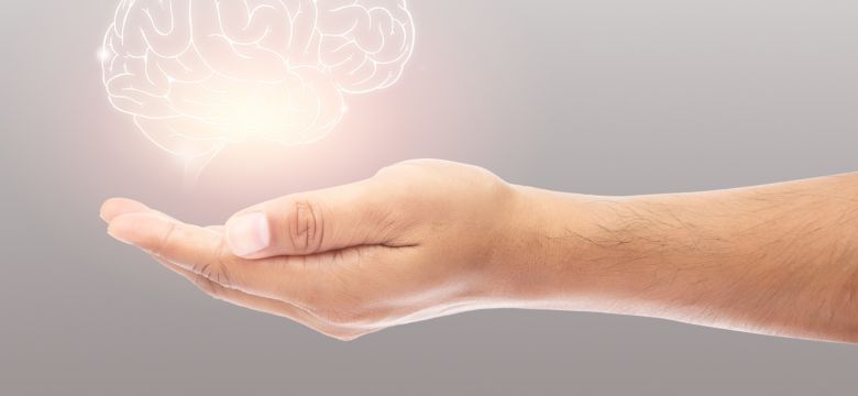 Man holding brain illustration against gray wall background. Concept with mental health protection and care.	