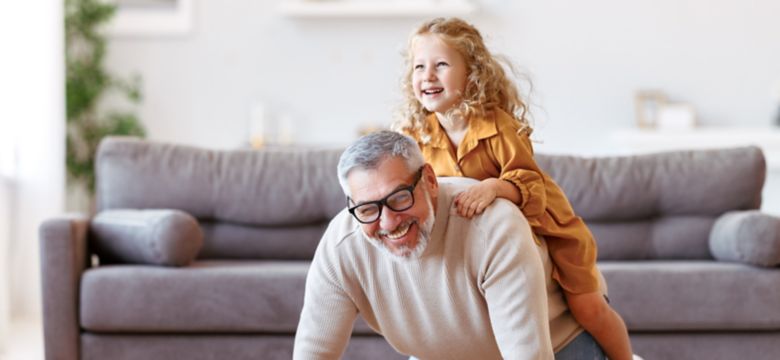 Cute little girl granddaughter playing and having fun with active positive grandfather, senior man grandpa giving piggyback to excited child and smiling at camera while taking care of kid at home; Shutterstock ID 2041162961; purchase_order: -; job: -; client: -