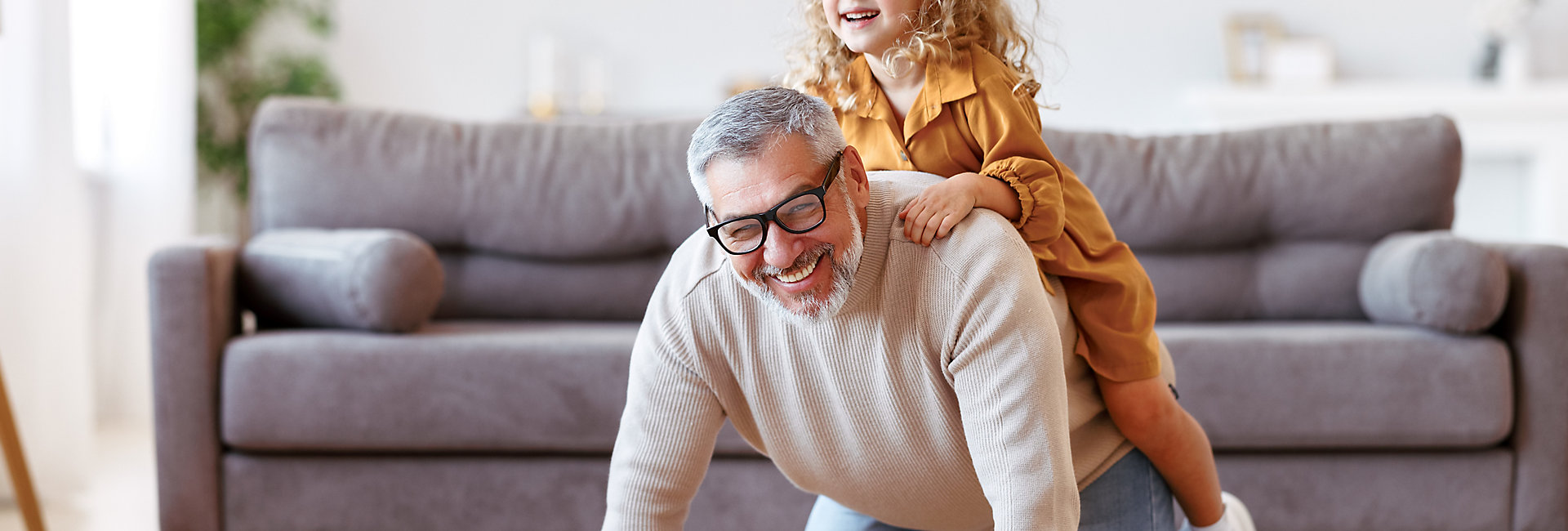 Cute little girl granddaughter playing and having fun with active positive grandfather, senior man grandpa giving piggyback to excited child and smiling at camera while taking care of kid at home; Shutterstock ID 2041162961; purchase_order: -; job: -; client: -