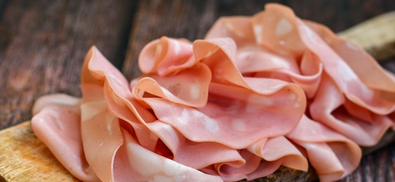 Slices Of  Traditional Italian antipasti mortadella Bolognese  on a wooden  cutting board.