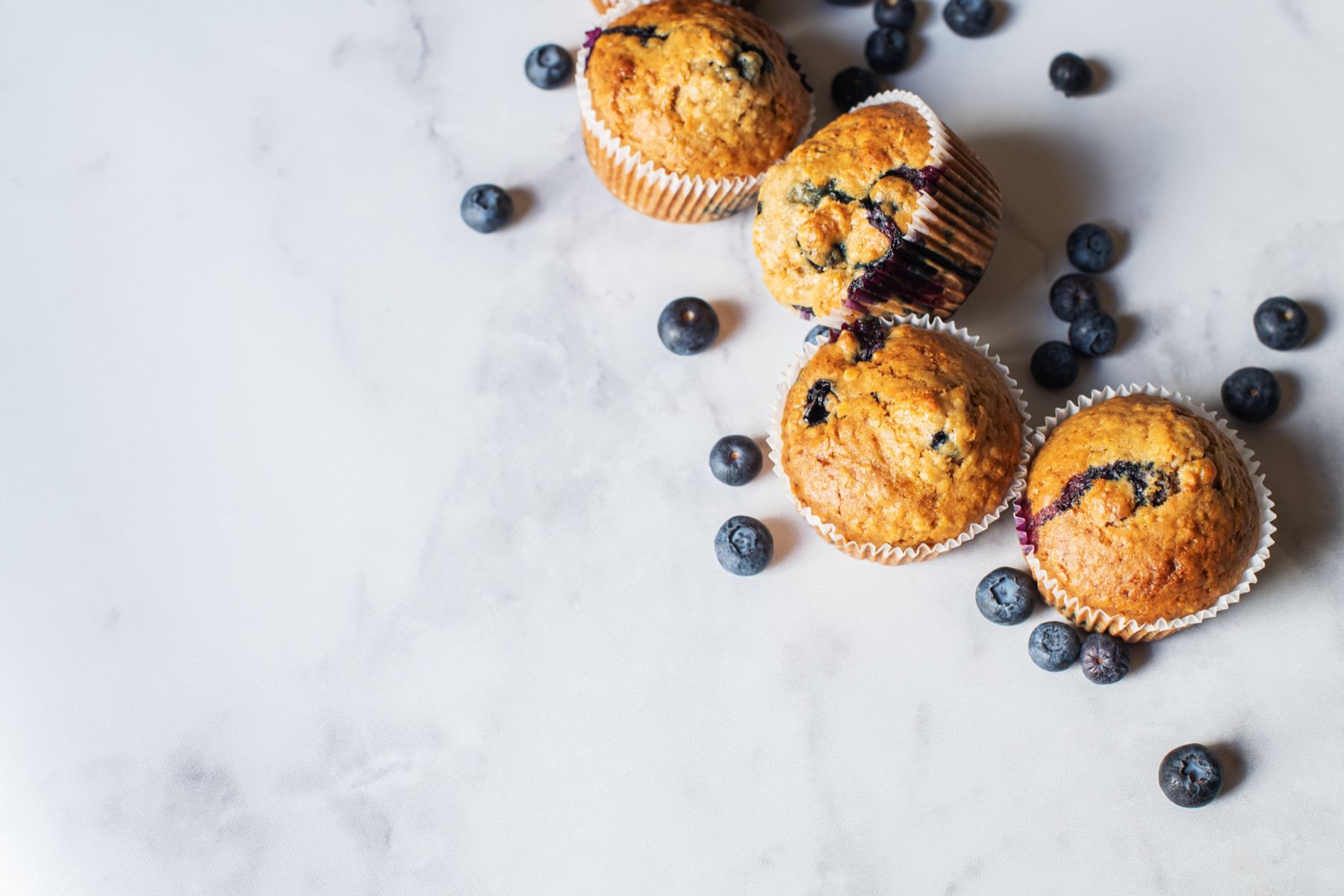 Blueberry muffins with blueberries on a grey marble table