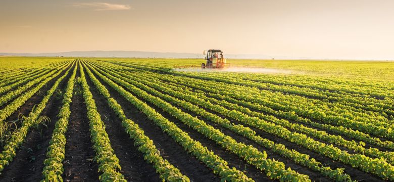 Tractor spraying pesticides on soybean field with sprayer at spring