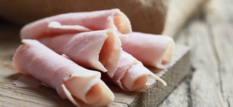 Sliced ham on wooden background.