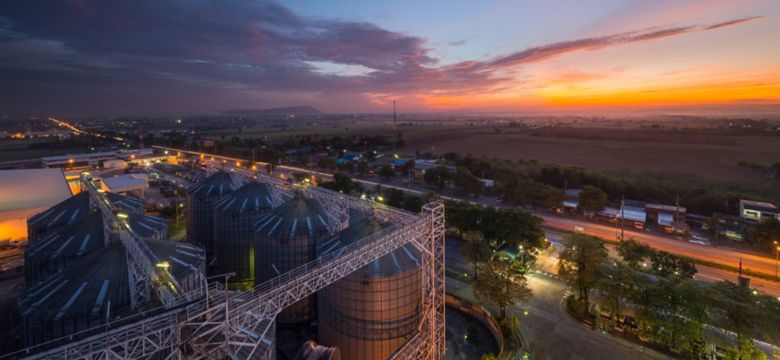 Silos of feed mill in front of red and orange sunset