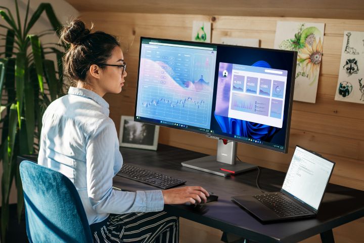 A woman using a mouse to edit a document on her monitor.