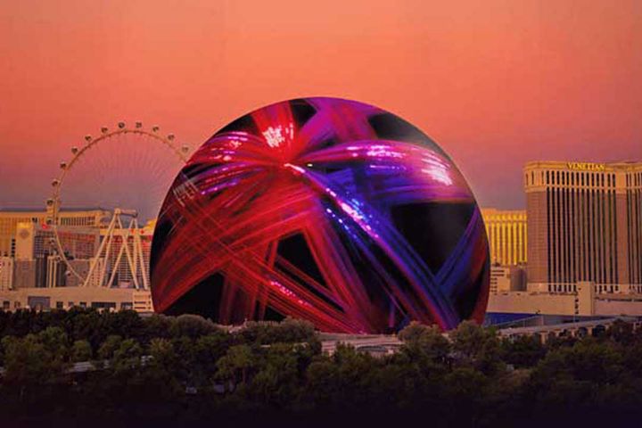The Las Vegas Sphere illuminated in red, blue, and purple lights. 