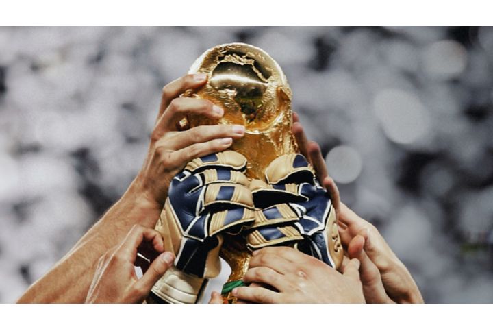 Hands holding up the Men’s World Cup trophy.
