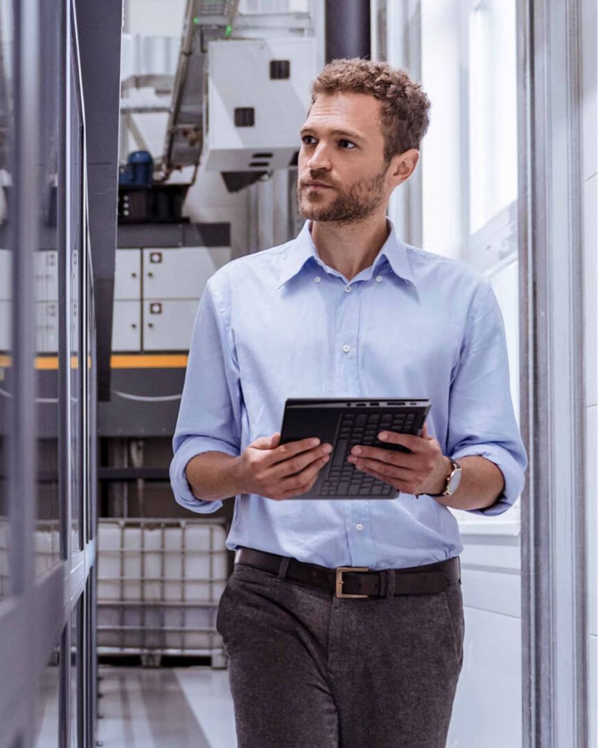 An IT guy holding a tablet and inspecting servers. 