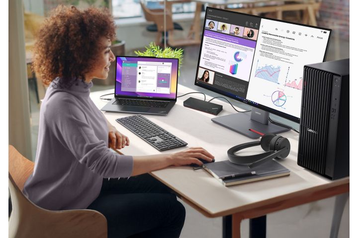 A woman working with two monitors, headphones, a keyboard, and mouse.