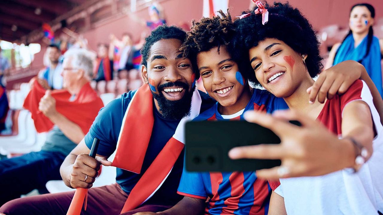 A family at a football match taking a selfie in the stands.