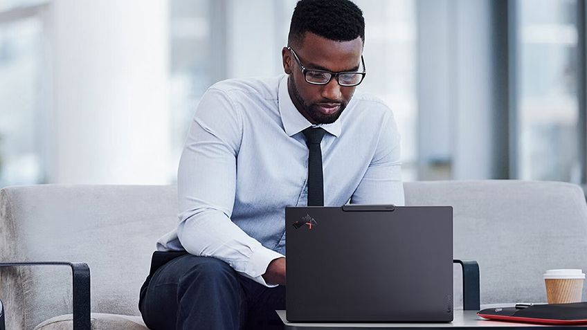 Professional working on a ThinkPad laptop with accessories for a mobile workspace