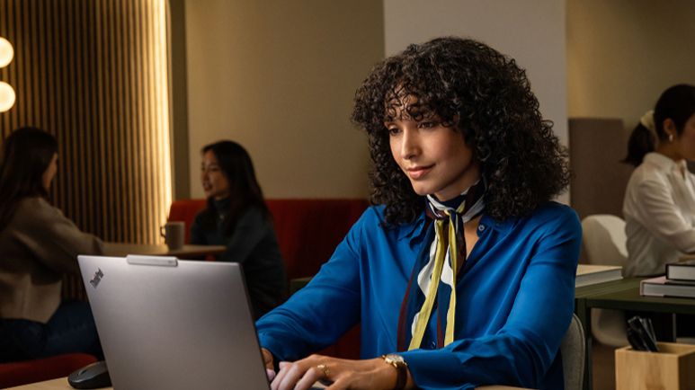 Une femme utilise un ordinateur portable dans un café faiblement éclairé.