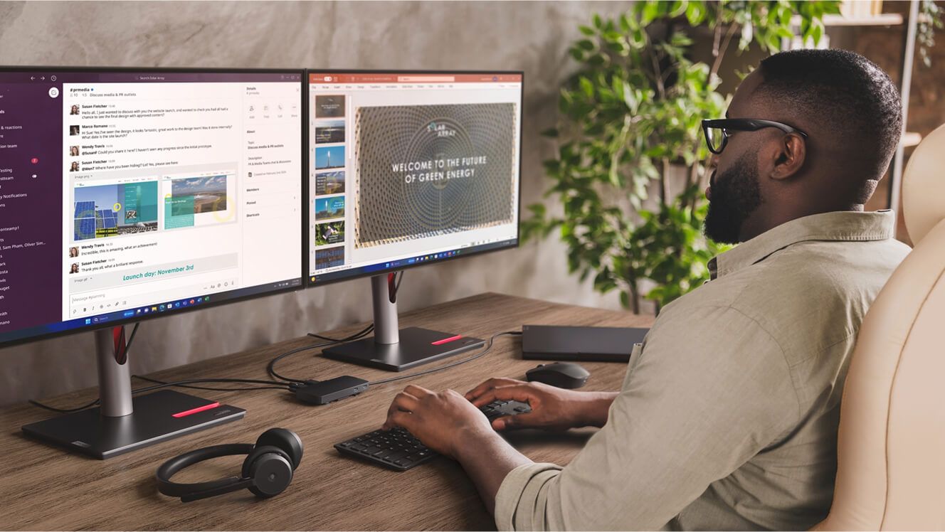 A man working with two monitors, headphones, a keyboard, and mouse.  
