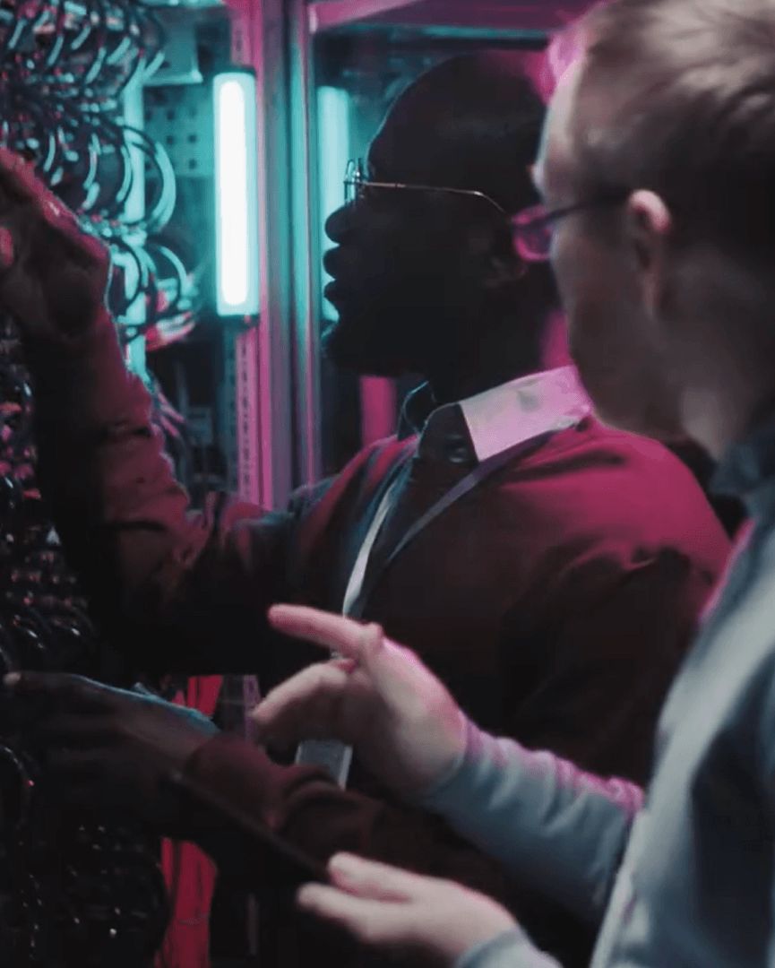 Two professionals examine server infrastructure in a data center.