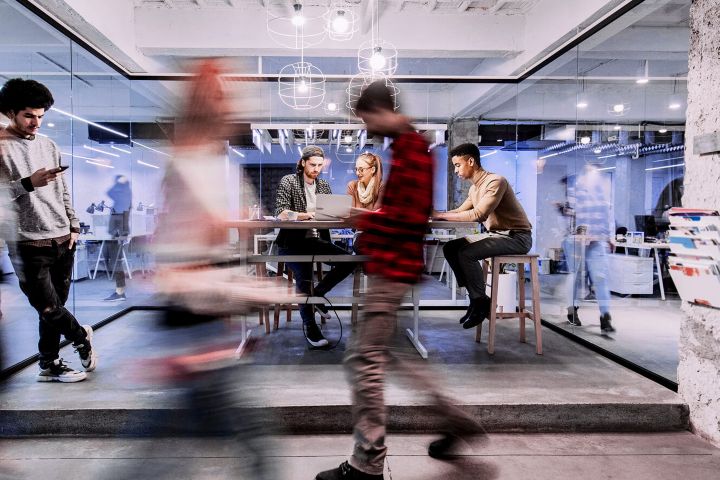 A time lapse of people working in a conference room and their colleagues walking past the glass-enclosed space.