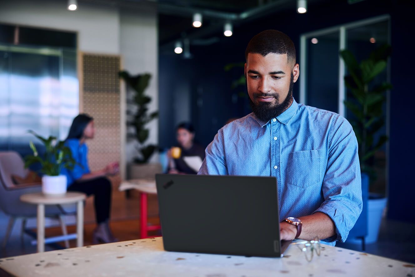A man working on his laptop in an open office.