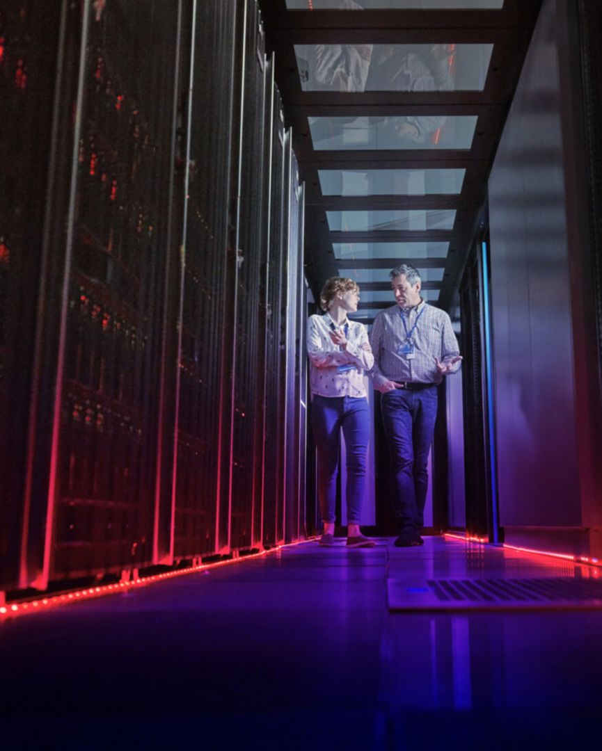 Woman and man walking through server room.