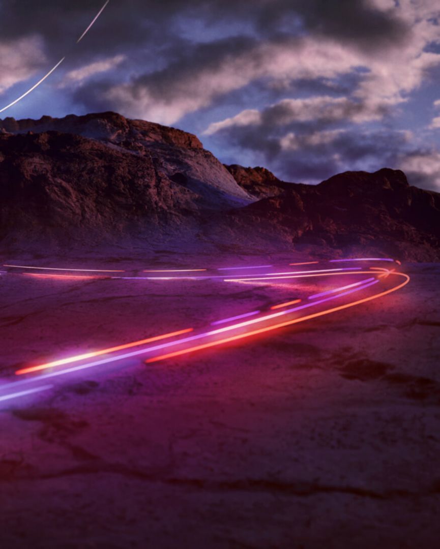 Blurred car lights from car driving fast through a mountain range at night.