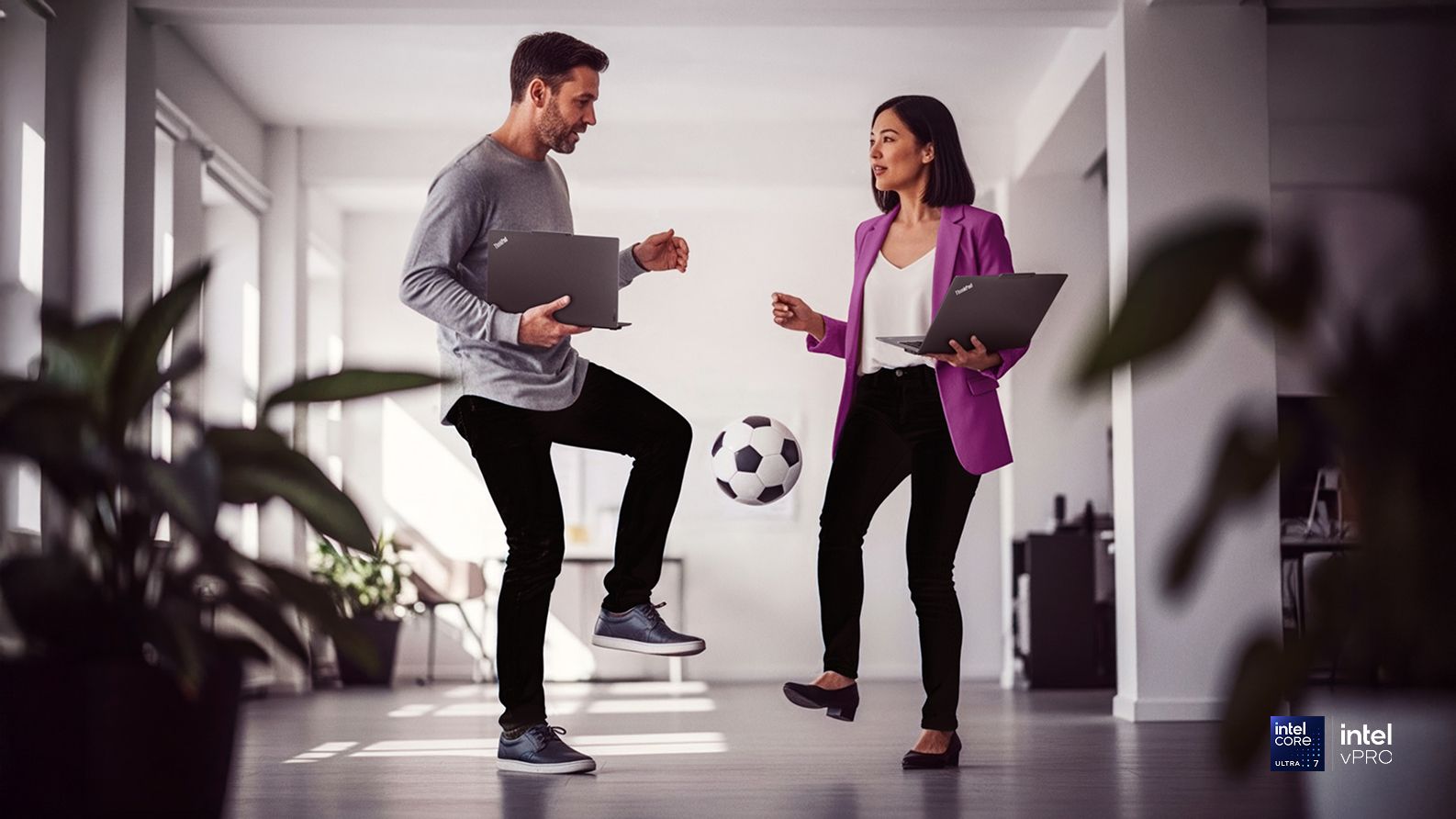 Two colleagues kicking a football in the hallway.